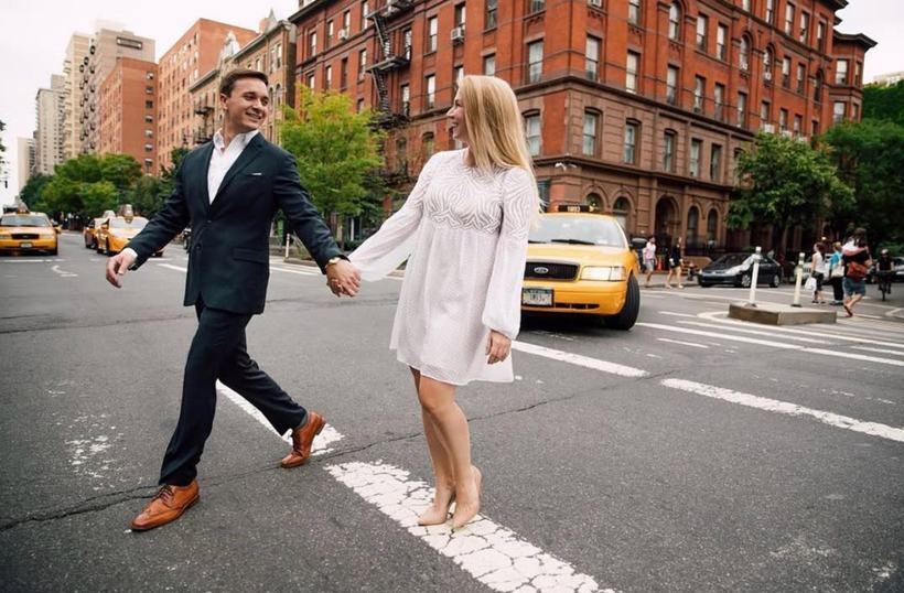 A couple walking hand in hand across a city crosswalk.