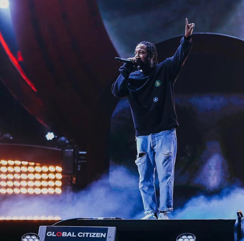 A performer with one arm raised on a smoky Global Citizen stage.
