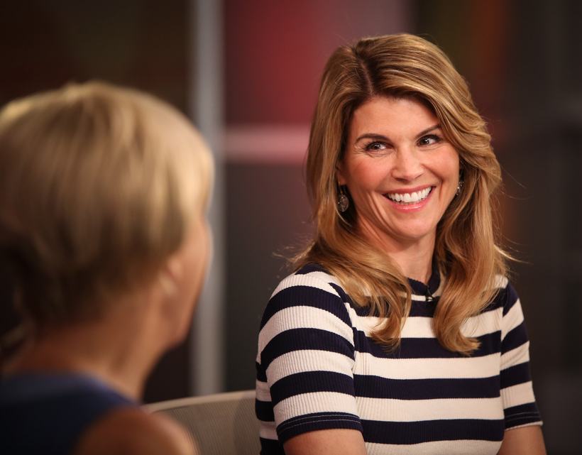 A smiling woman in a striped top being interviewed.
