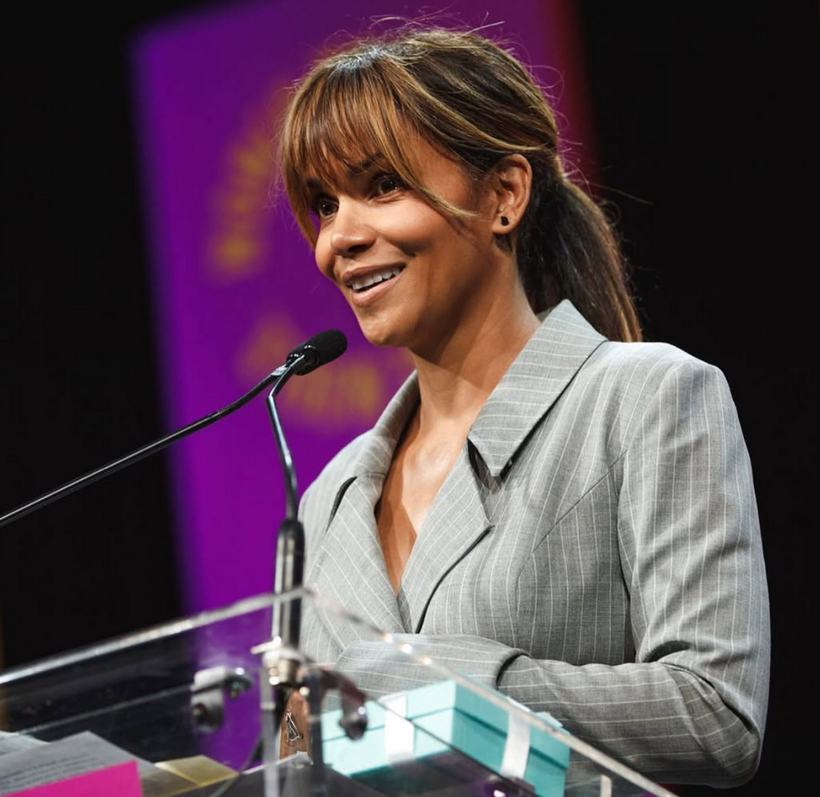 A woman speaking at a podium microphone on stage.