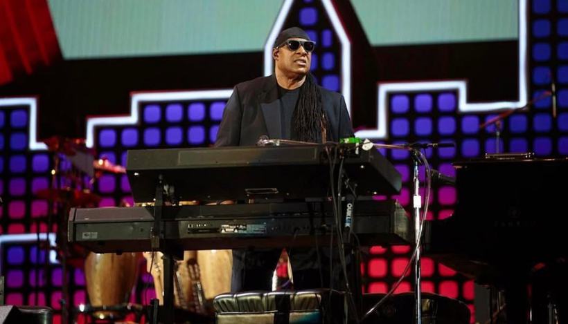A musician at a keyboard on a stage lit in red, white and blue.