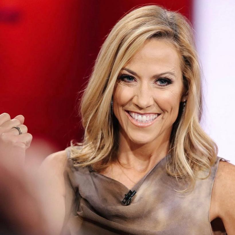 A woman laughing during a television interview.