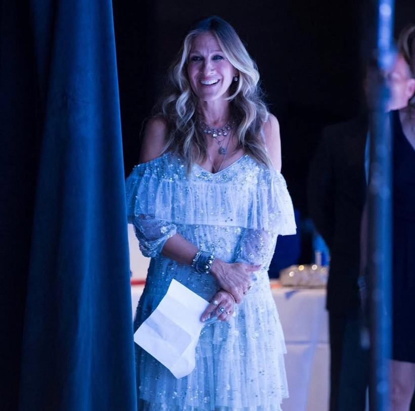 A woman in a white dress holding cue cards on a blue-lit stage.