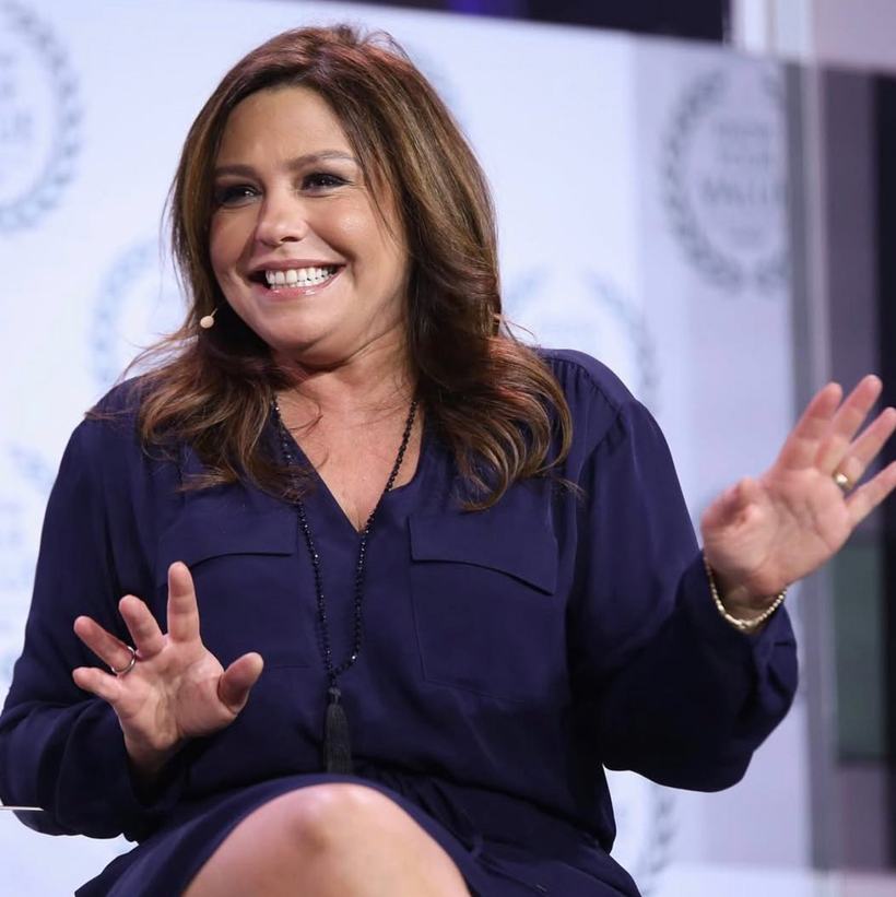 A woman in navy gesturing mid-conversation on stage.