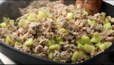 A cast iron skillet of browned filling with diced zucchini.